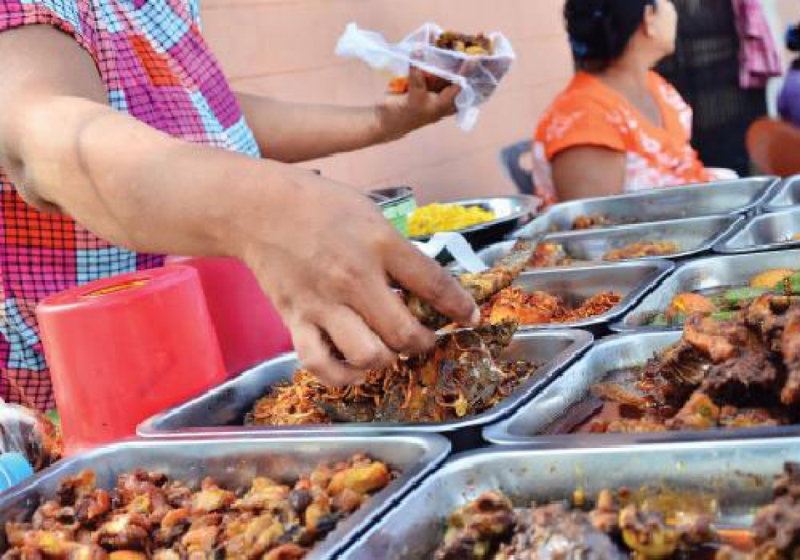 A street food vendor picks up a piece of fish to serve to a customer. Aung Htay Hlaing/ The Myanmar Times